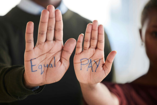 The words "Equal Pay" written on the extended hands of two employees.